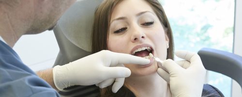 Zahnarzt setzt Zahn bei Patientin ein