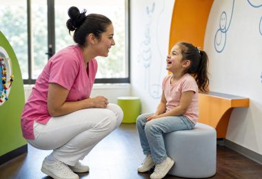 Mitarbeiterin von 360°milchzahn im Gespräch mit einem Kind im Kinderbereich der Praxis